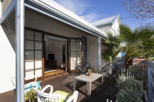 een huis met een patio met een tafel en stoelen bij Sweetgum on Lefroy in South Fremantle