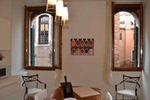 un soggiorno con due finestre, un tavolo e sedie di Ca' Bacio della Luna a Venezia