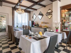 a restaurant with white tables and chairs and a chandelier at Villa Louvre Lens in Lens