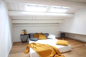 a bedroom with a white bed and yellow pillows at Pànto - Rooftop boutique rooms in Palermo