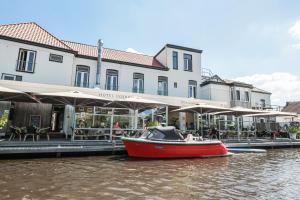 un barco rojo en el agua frente a un edificio en Hotel Restaurant Goerres, en Akkrum