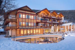 a large building with snow in front of it at Hotel Villa Stefania in San Candido