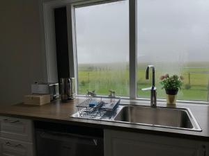 a kitchen with a sink and a large window at Setberg Guesthouse in Nesjum