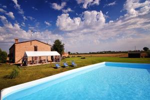 a swimming pool in front of a building with a marquee at Il Frattiero B&B in Voghenza