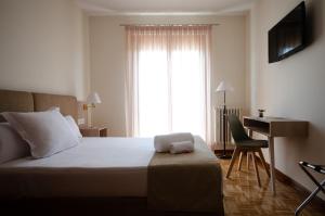 Schlafzimmer mit einem Bett, einem Schreibtisch und einem Fenster in der Unterkunft Hotel Puerta Ciudad Rodrigo in Ciudad-Rodrigo