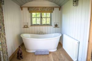 a white bath tub in a bathroom with a window at Perkins luxury shepherd huts in Nottingham