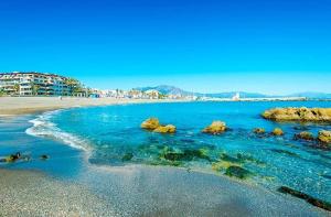 a beach with rocks and blue water and buildings at Princesa Kristina in Manilva