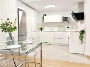 una cocina con armarios blancos y una mesa y sillas de cristal. en Deluxe Beach Flat w Garage by Wave Properties en Las Palmas de Gran Canaria