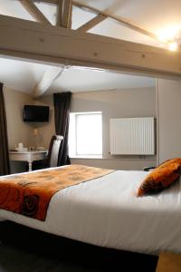 a bedroom with a large bed and a desk at Logis Hostellerie de l'Abbaye in Celles-sur-Belle
