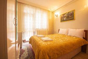 ein Schlafzimmer mit einem Bett mit gelber Tagesdecke und einem Fenster in der Unterkunft AWWA APART HOTEL in Istanbul