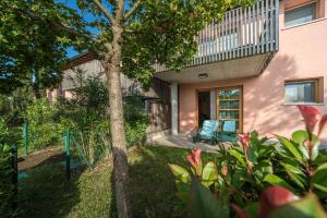 ein Haus mit einem Baum und zwei Stühlen im Hof in der Unterkunft Green Village Eco Resort in Lignano Sabbiadoro