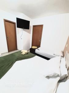 Habitación blanca con cama y TV de pantalla plana. en Flats Bueno em Goiânia, en Goiânia