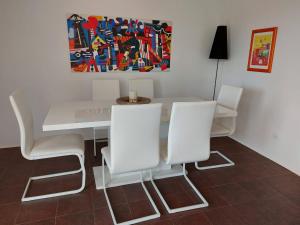 a white dining room table with white chairs and a painting at Apartments Coral of Dubrovnik in Dubrovnik