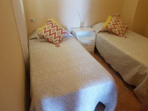 1 dormitorio con 2 camas y mesita de noche con falda en Apartamentos Las Salinas 2, en Caleta de Interián