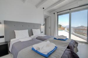 two beds in a room with a large window at Pyrgos Exclusive , Sea View & Private Pool in Sellía