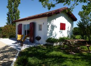 una pequeña casa blanca con una mesa de picnic en el patio en Gîte Etchola, en Ramous