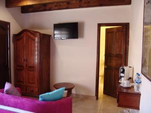 a living room with a purple couch and a tv at Casa del Tio Hotel Boutique in San Miguel de Allende