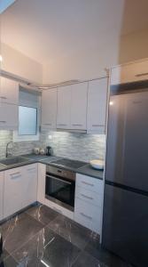 a kitchen with white cabinets and a stainless steel refrigerator at Di fronte alla fortezza in Nafplio