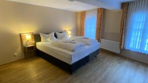 a bedroom with a bed with white sheets and two windows at Horchem Hotel-Restaurant-Café-Bar in Monschau