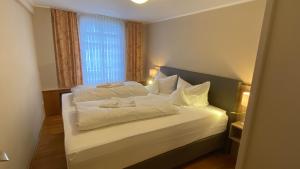 a bedroom with a bed with white sheets and a window at Horchem Hotel-Restaurant-Café-Bar in Monschau