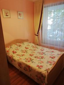 a bedroom with a bed with a floral bedspread at Comfort Zamenhof in Varna City