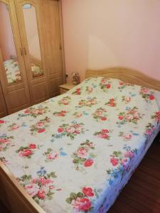 ein Bett mit einer Blumendecke darauf in der Unterkunft Comfort Zamenhof in Warna