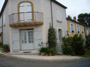 une maison blanche avec un balcon dans une rue dans l'établissement Chez Edèll, à Monpazier