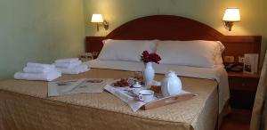 una camera d'albergo con letto, asciugamani e vassoio di cibo di Hotel Squarciarelli a Grottaferrata