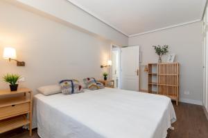 1 dormitorio blanco con 1 cama blanca grande con almohadas en Confortable piso en Neguri, a 5 min de la playa, en Getxo