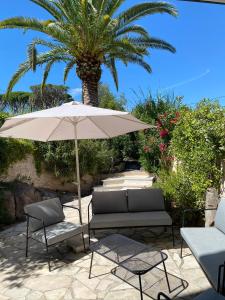 eine Terrasse mit einem Sonnenschirm, Stühlen und einer Palme in der Unterkunft SIMONE, Appartement maison, quartier calme, grande terrasse, SPA, barbecue, 2 chambres in Fréjus
