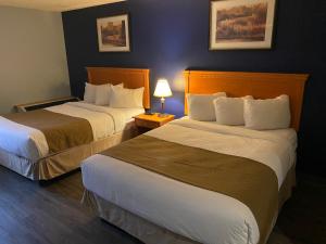 a hotel room with two beds and a lamp at Northern Star Hotel & Convention Center in Slave Lake