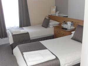 a hotel room with two beds and a mirror at Powys Lodge in Scarborough