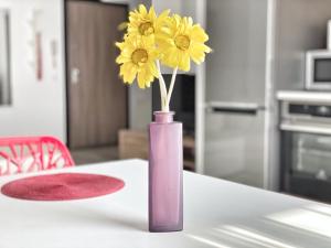 ママイアにあるArianna Residence Summerlandのテーブルの上に黄色い花が咲く紫の花瓶