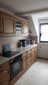 a kitchen with wooden cabinets and a stove top oven at Ferienwohnung Liebscher in Sehmatal