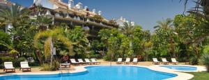 a resort with a pool and chairs and a building at Lomas del Rey in Marbella