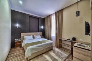 Habitación de hotel con cama y TV en Level en Osh
