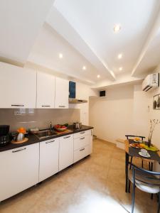 a large kitchen with white cabinets and a table at Apartament Colosseum view in Pula