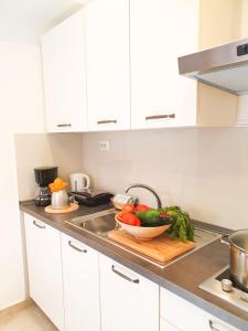 a kitchen counter with a bowl of vegetables on a cutting board at Apartament Colosseum view in Pula