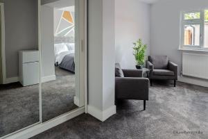 Cette chambre comprend un miroir, une chaise et un lit. dans l'établissement Like Your Own Private Hotel, à Luton
