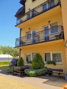 a yellow building with two benches in front of it at Pensjonat Bryza in Karwia
