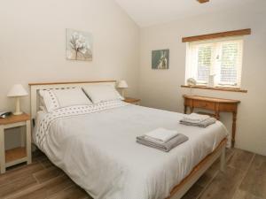 a bedroom with a bed with white sheets and a window at Golson Stable in Spalding