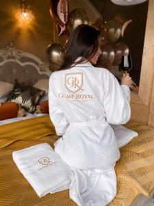 kobieta siedząca na łóżku trzymająca kieliszek wina w obiekcie Glamp Royal w Białym Dunajcu