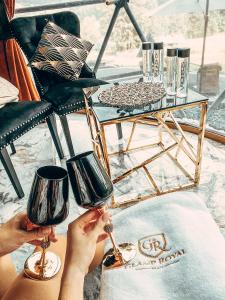 uma pessoa segurando dois copos de vinho ao lado de uma mesa em Glamp Royal em Biały Dunajec