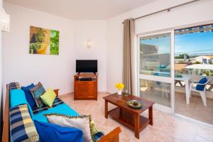 un salon avec un canapé bleu et une télévision dans l'établissement Apartamentos Casa Brito, Boliqueime by AlgarveBlossom, à Boliqueime