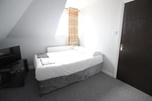 ein kleines Schlafzimmer mit einem Bett und einem Fenster in der Unterkunft Clock House Hotel - London Croydon in Croydon