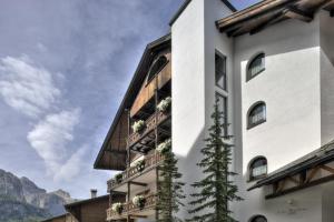 un bâtiment avec un arbre sur son côté dans l'établissement Hotel La Tambra, à Corvara in Badia