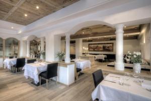 un restaurant avec des tables blanches, des chaises et des colonnes dans l'établissement Hotel La Tambra, à Corvara in Badia