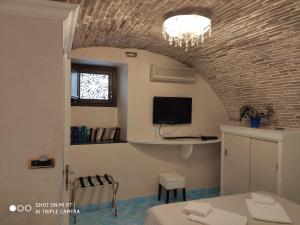 Zimmer mit einem Tisch und einem TV an einer Backsteinwand in der Unterkunft B&B Vescovo Pitirro in Termoli