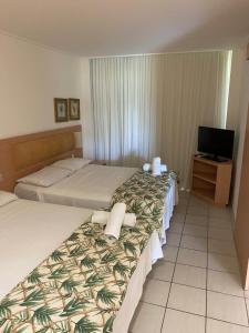 ein Hotelzimmer mit zwei Betten und einem Fernseher in der Unterkunft Beach Class Slin Muro Alto in Porto De Galinhas + 36 Fotos
