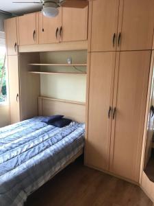 a bedroom with a bed and wooden cabinets at POA zona norte - melhor opção - completíssimo in Porto Alegre